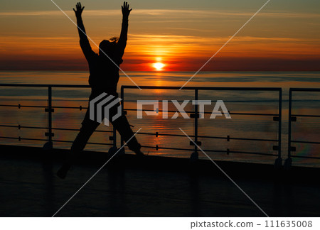 Girl silhouette in magical sunset over the Gulf of Finland, Baltic sea. Girl silhouette in magical sunset over the Gulf of Finland, Baltic sea. 111635008