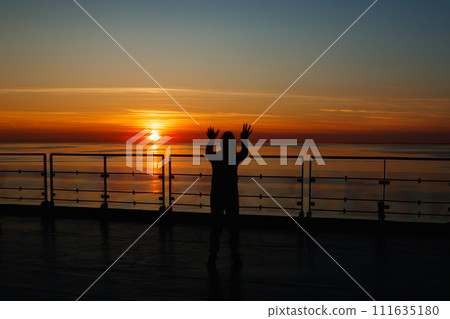 Girl silhouette in magical sunset over the Gulf of Finland, Baltic sea. Girl silhouette in magical sunset over the Gulf of Finland, Baltic sea. 111635180