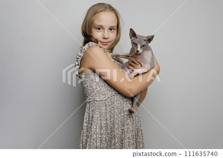 Pretty child girl hugging cat pet on gray studio wall banner background 111635740