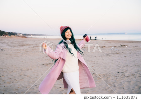 Smiling stylish hipster woman with color hair having fun on the beach, running and dancing on the sand. Happy woman. Off season Travel and freedom concept. Seasonal street fashion. Simple pleasures Smiling stylish hipster woman with color hair having fun on the beach, running and dancing on the sand. Happy woman. Off season Travel and freedom concept. Seasonal street fashion. Simple pleasures 111635872