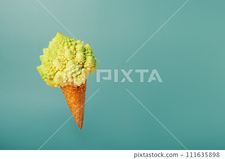 Plant based Ice cream concept. Waffle cone with vegetable. Decorative Romanesco cabbage as a vegetarian dessert flying on pastel green background. Creative healthy vegetarian and vegan food concept. Plant based Ice cream concept. Waffle cone with vegetable. Decorative Romanesco cabbage as a vegetarian dessert flying on pastel green background. Creative healthy vegetarian and vegan food concept. 111635898