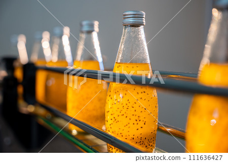 Quality manufacturing in the bottling factory is visible as transparent bottles are filled with basil or chia seed drinks infused with pomegranate. This automated process ensures a healthy outcome. Quality manufacturing in the bottling factory is visible as transparent bottles are filled with basil or chia seed drinks infused with pomegranate. This automated process ensures a healthy outcome. 111636427