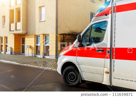 German Ambulance EMS paramedic rescue van transport parked on European city street suburb neighborhood on sunny day after rain. Medical urgent service help vehicle 111639871