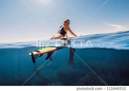 Surfer woman in sexy bikini on surfboard in clear ocean. Water activity lifestyle on summer vacation 111640532