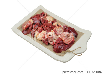 Raw chicken giblets on a ceramic board. Isolated on white background. Chicken stomachs, hearts and livers are prepared for cooking. Raw chicken giblets on a ceramic board. Isolated on white background. Chicken stomachs, hearts and livers are prepared for cooking. 111641082