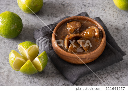 Traditional Sri Lankan Lime Pickle of lime, salt, chilli, pepper in glass preserve jar on gray background. Close up. Ceylon cuisine. 111641257