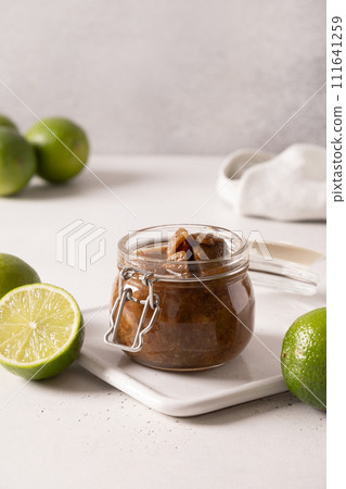 Popular Sri Lankan lime pickle with salt, chilli, pepper in glass jar on gray background. Vertical format. Popular Sri Lankan lime pickle with salt, chilli, pepper in glass jar on gray background. Vertical format. 111641259