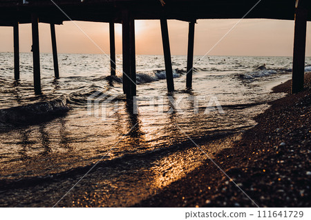 beautiful evening landscape on the sea. sunset of the setting sun. the sun disappeared behind the horizon of the sea. sea view through the pillars of the embankment.Turkey Mediterranean Sea beautiful evening landscape on the sea. sunset of the setting sun. the sun disappeared behind the horizon of the sea. sea view through the pillars of the embankment.Turkey Mediterranean Sea 111641729