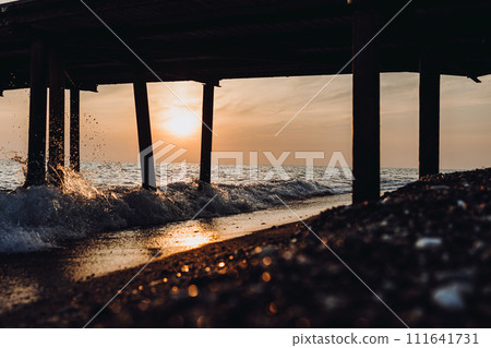 beautiful evening landscape on the sea. sunset of the setting sun. the sun disappeared behind the horizon of the sea. sea view through the pillars of the embankment.Turkey Mediterranean Sea beautiful evening landscape on the sea. sunset of the setting sun. the sun disappeared behind the horizon of the sea. sea view through the pillars of the embankment.Turkey Mediterranean Sea 111641731