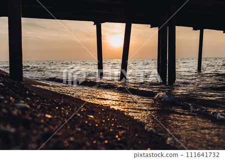 beautiful evening landscape on the sea. sunset of the setting sun. the sun disappeared behind the horizon of the sea. sea view through the pillars of the embankment.Turkey Mediterranean Sea beautiful evening landscape on the sea. sunset of the setting sun. the sun disappeared behind the horizon of the sea. sea view through the pillars of the embankment.Turkey Mediterranean Sea 111641732