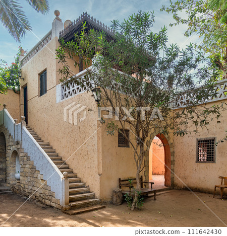 Tranquil courtyard showcasing traditional building style and flora, inviting a sense of serenity and historical charm 111642430
