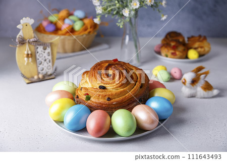 Craffin (Cruffin) with raisins and candied fruits. Traditional Easter Bread Kulich and painted eggs on a gray background. Easter Holiday. Close-up, selective focus. 111643493
