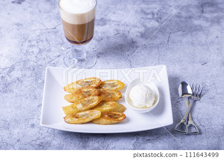 Fried bananas with honey, cinnamon, coffee and ice cream. Close-up. Fried bananas with honey, cinnamon, coffee and ice cream. Close-up. 111643499
