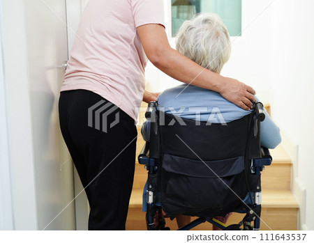 Asian senior woman on wheelchair with caregiver help support walking down the stairs prevent accident, slip and fall at home. Asian senior woman on wheelchair with caregiver help support walking down the stairs prevent accident, slip and fall at home. 111643537