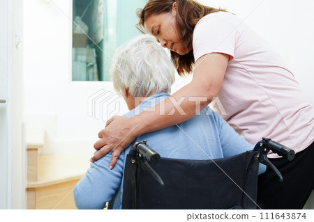 Asian senior woman on wheelchair with caregiver help support walking down the stairs prevent accident, slip and fall at home. Asian senior woman on wheelchair with caregiver help support walking down the stairs prevent accident, slip and fall at home. 111643874