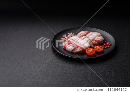 Round minced chicken or pork cutlet wrapped in bacon with salt, spices and herbs 111644132