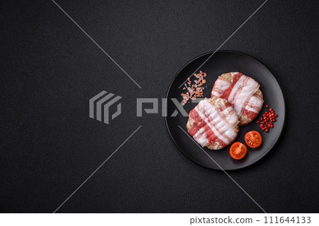 Round minced chicken or pork cutlet wrapped in bacon with salt, spices and herbs Round minced chicken or pork cutlet wrapped in bacon with salt, spices and herbs 111644133