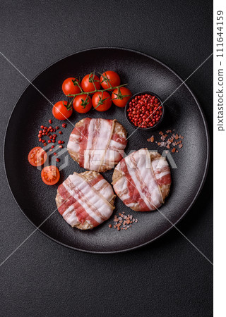 Round minced chicken or pork cutlet wrapped in bacon with salt, spices and herbs Round minced chicken or pork cutlet wrapped in bacon with salt, spices and herbs 111644159