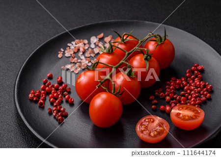 A branch of raw cherry tomatoes with salt and spices on a dark background A branch of raw cherry tomatoes with salt and spices on a dark background 111644174