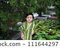 lovely boy dressed up in Japanese costume in water lily garden  111644297