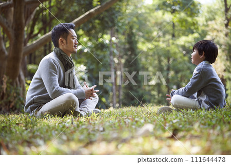 young asian father having a pleasant conversation with son outdoors young asian father having a pleasant conversation with son outdoors 111644478