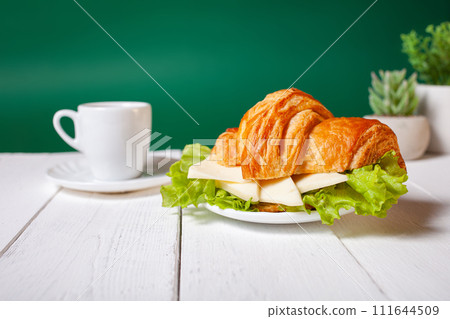 Minimalism, food on a background. Empty text space, mocap. Croissant with cheese sausage greens. Minimalism, food on a background. Empty text space, mocap. Croissant with cheese sausage greens. 111644509