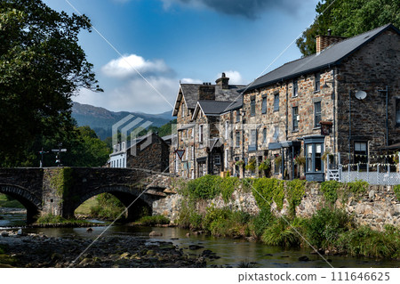Stone Bridge And River In The City Of Beddgelert In Snowdonia National Park In Gwynedd, Wales, United Kingdom Stone Bridge And River In The City Of Beddgelert In Snowdonia National Park In Gwynedd, Wales, United Kingdom 111646625