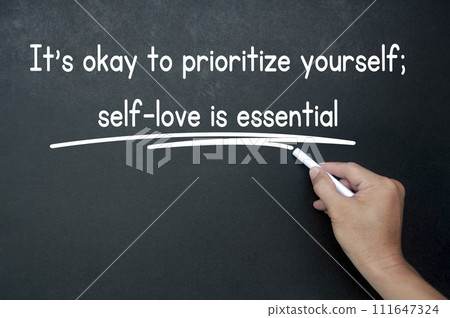 Hand writing It is okay to prioritize yourself affirmation on black board. Affirmation concept. Hand writing It is okay to prioritize yourself affirmation on black board. Affirmation concept. 111647324