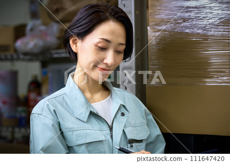 一名穿著工作服的婦女在倉庫盤點庫存 111647420