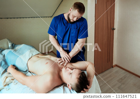 Chest massage for young man at home by mobile massage therapist. Chest massage for young man at home by mobile massage therapist. 111647521