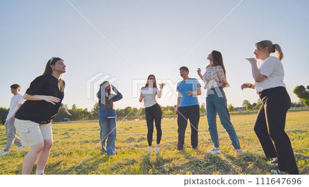 Funny jolly friends dancing in the city meadow in the evening. 111647696