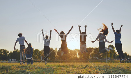 Group of five happy friends jumps at sunset time on background mountains. 111647754