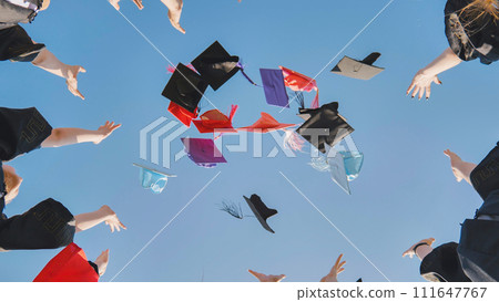Graduates tossing multicolored hats against a blue sky. Graduates tossing multicolored hats against a blue sky. 111647767