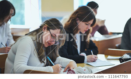 Girl students writing math formulas in a notebook. 111647793