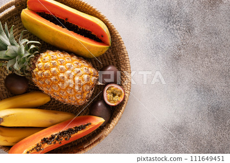 Popular Asian exotic fruits pineapple, passion fruit and papaya served in tray on gray background. Top view, copy space. Popular Asian exotic fruits pineapple, passion fruit and papaya served in tray on gray background. Top view, copy space. 111649451