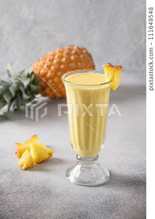 Asian traditional Pineapple lassi on gray background. Freshness cold beverage made of yogurt, water, spices, fruits and ice. Popular beverage in India and Sri lanka. Vertical format. Asian traditional Pineapple lassi on gray background. Freshness cold beverage made of yogurt, water, spices, fruits and ice. Popular beverage in India and Sri lanka. Vertical format. 111649548