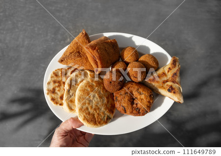 Authentic Sri Lankan different street food, short eats served in white plate in womans hand. Vegetable roti, Chinese rolls, coconut roti, cutlets, mutton rolls. Snacks made with tuna, potatoes, onion Authentic Sri Lankan different street food, short eats served in white plate in womans hand. Vegetable roti, Chinese rolls, coconut roti, cutlets, mutton rolls. Snacks made with tuna, potatoes, onion 111649789