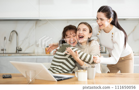 Women are sitting at computer and are immensely happy Women are sitting at computer and are immensely happy 111650056