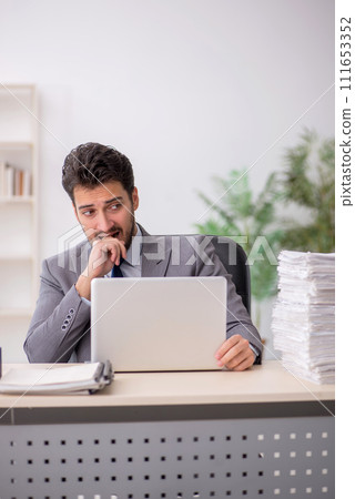 Young male employee and too much work in the office 111653352