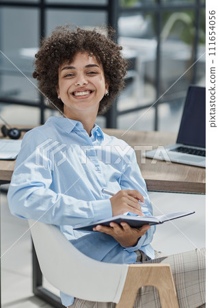 Happy female designer standing in office Happy female designer standing in office 111654056