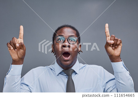 young african american man surprised showing fingers up on gray background 111654665