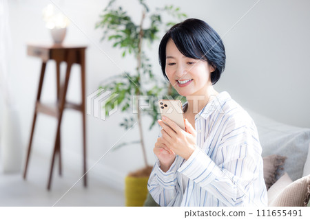 在客廳裡操作智能手機的中年女人 111655491