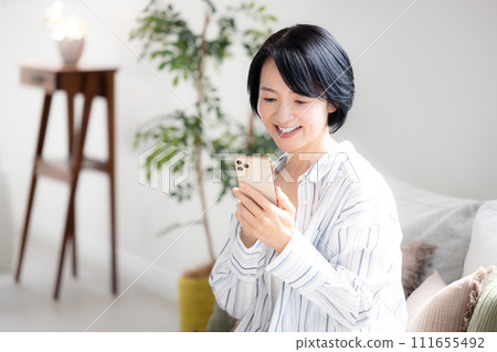 在客廳裡操作智能手機的中年女人 111655492