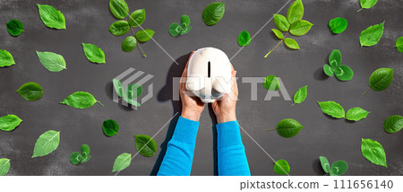 Person holding a piggy bank with green leaves Person holding a piggy bank with green leaves 111656140