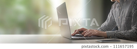 一個人在靠窗的桌子上用筆記型電腦打字 111657195