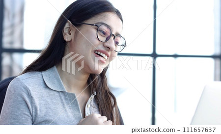 A young woman with glasses in the office is talking on an online video connection 111657637