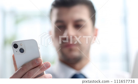 A male businessman uses a phone in close-up A male businessman uses a phone in close-up 111657738