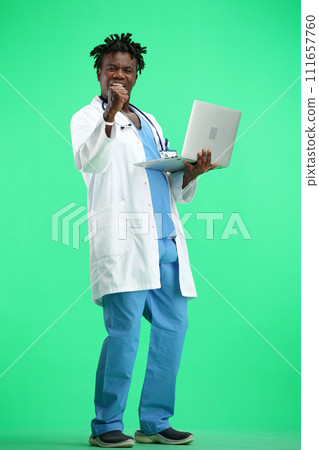 The doctor, in full height, on a green background, uses a laptop The doctor, in full height, on a green background, uses a laptop 111657760