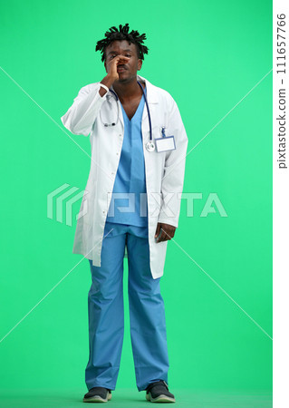 The doctor, in full height, on a green background, tells a secret 111657766