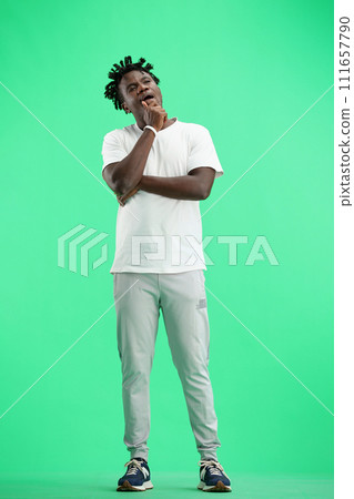 A man, full-length, on a green background, yawns 111657790